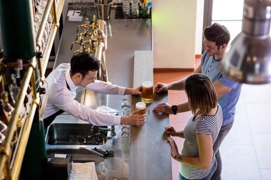 Bartender serving beer to couple 
