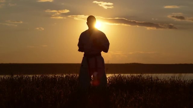 Silhouette of man training karate at sunset. Slow motion.