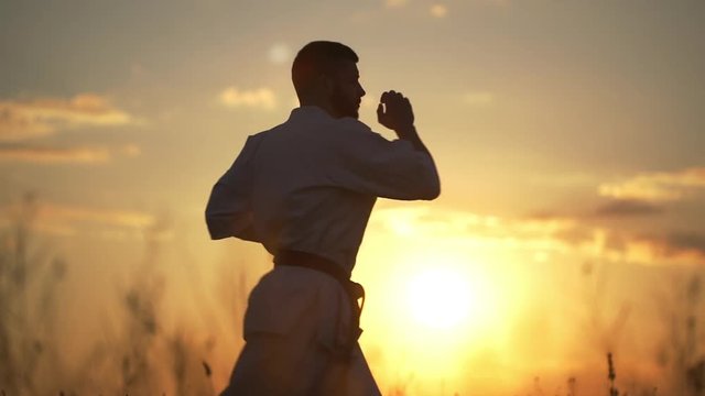 Silhouette of man training karate at sunset. Slow motion.