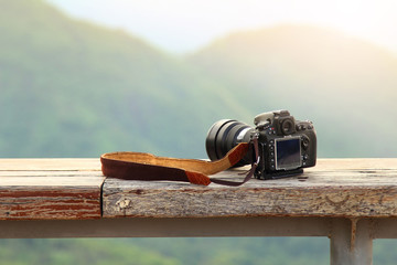 Dslr photo camera is travel photographer equipment placed on a wooden terrace with a beautiful background of natural.Traveling and Relax Concept
