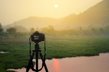 Dslr photo camera on tripod is travel photographer equipment shooting atmosphere during sunrise,sunset (with clipping path).Traveling and Relax Concept