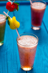 Variety of Fresh Healthy Paleo Smoothies and Cocktails in Rainbow Colors on Blue Wooden Background, Beach Party