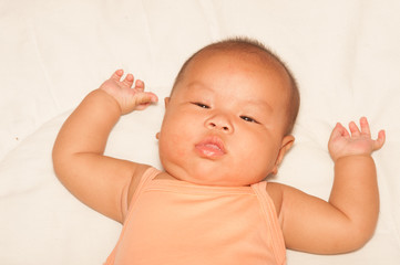 Newborn Asian baby girl lying on a bed.