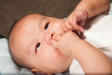 Newborn Asian baby girl lying on a bed.