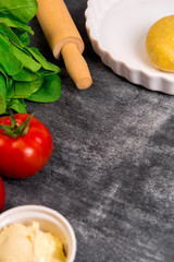 Vegetables and dough over grey wooden background