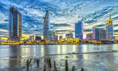 Fototapeta na wymiar Ho Chi Minh City, Vietnam - June 29th, 2016: Moments between day and night twilight urban centers waterfront side when skyscrapers with bright lights adorn country development