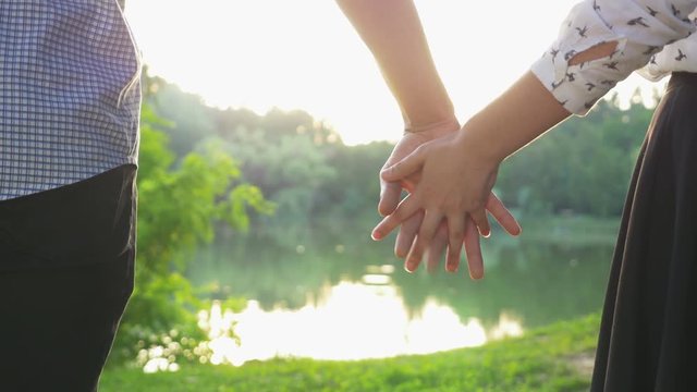 Close-up of couple holding hands at sunset and walking together