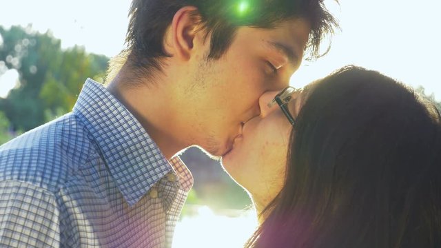 Close-up of loving couple kissing at sunset and looking into the horizon