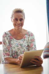 Senior woman looking at the camera using a digital tablet