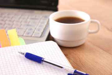 Office table with blank notepad and laptop