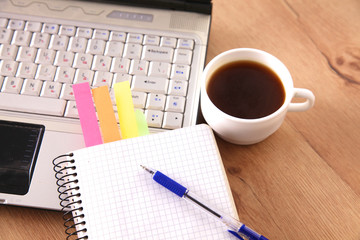 Office table with blank notepad and laptop