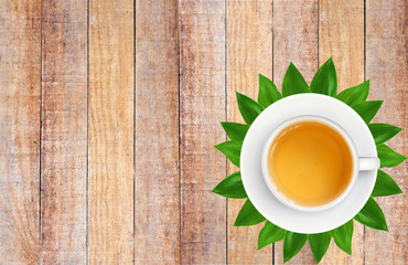 White Tea Cup on Green Leaves on Brown Old Wood Plank Texture Ba