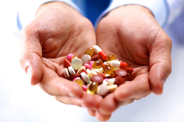 A young doctor holds the patient's hand with pills