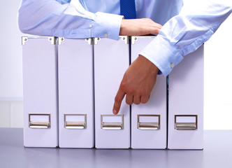 businessman standing over a folder with documents