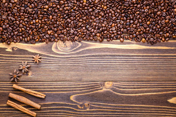 Grains of coffee on a brown wooden background with cinnamon sticks