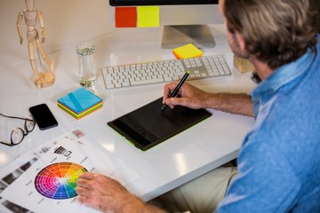 Businessman using graphics tablet at desk 