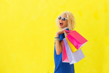 Funny woman holding shopping bags over her shoulder