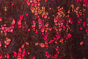 The cracked red paint on an old metallic surface.