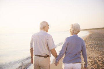 Holding hands while walking on the beach.