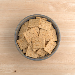 Bowl of organic whole wheat crackers on a wood table top view.
