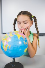Schoolgirl looking at globe in classroom