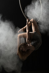 Acrobatic woman doing trick on aerial hoop with sprinkled flour © antgor
