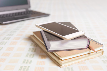 Naklejka premium Smartphone, books, pencil, computer, all on bed