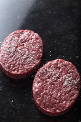 Meat for burgers, grilling, barbecue, bbq. Fresh, spicy, uncooked, delicious beef for hamburgers on dark background with copy space closeup
