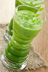 Green spinach smoothie / Spinach and green apple smoothie in glass with straw on wooden background