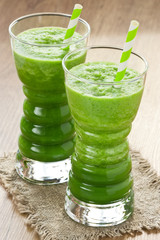 Green spinach smoothie / Spinach and green apple smoothie in two glass with straw on wooden background