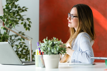 Beautiful young woman working with laptop in her office.