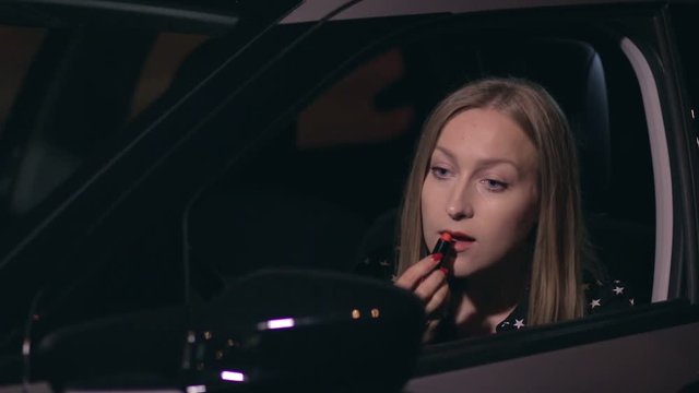 Pretty woman driver in a car doing makeup