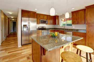 Spacious kitchen room with bar, stainless steel appliances and pendant lights.