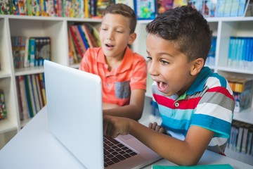 Schoolkids using laptop in library