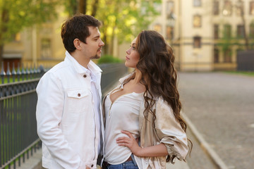 Fototapeta premium Fashion portrait of young couple in love posing at street. Beautiful girl and handsome boy hugging outdoors
