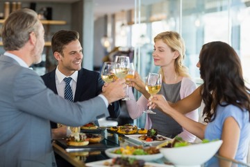 Business colleagues toasting beer glasses while having lunch