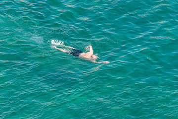 man swimming in a transparent sea water
