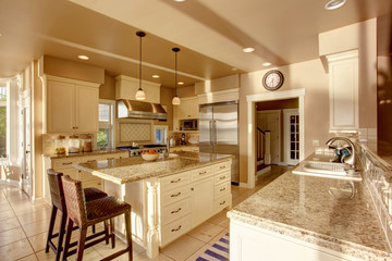 Large luxury kitchen room in beige colors with granite counter tops and tile floor.