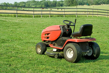 Lawnmower in Pasture – A lawnmower sitting in the newly-mown pasture. Fence and hay bales in background.