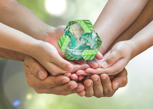 Parent guardian children hands holding together recycled green leaf arrow sign planet on blur nature greenery background sun flare Environment CSR ESG concept Element of this image furnished by NASA