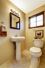 Bright beige bathroom interior with old washbasin stand, toilet and tile floor.