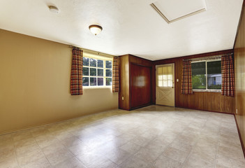 Empty spacious entryway with wooden wall and tile floor.