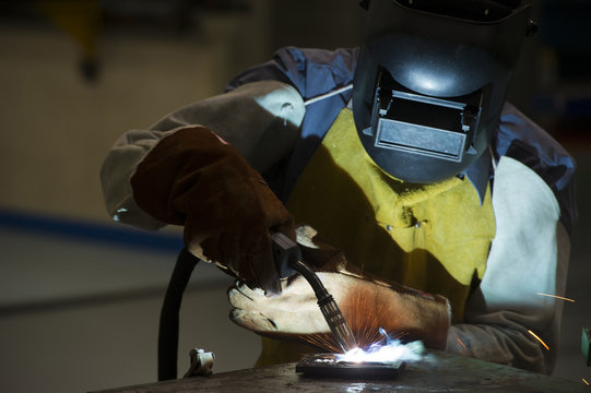 man welding steel by skill.Men wear protective clothing during work.