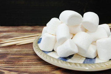 Fluffy white marshmallow in wooden bowl on old wooden table