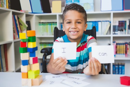 Disabled boy showing placard that reads I Can in library
