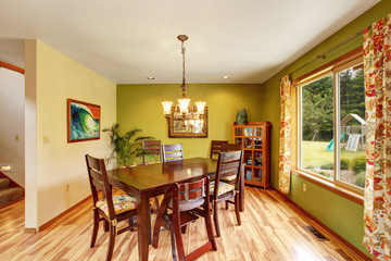 Antique green dining room interior with mahogany table set and chandelier.