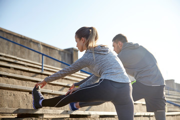 couple stretching leg on stands of stadium