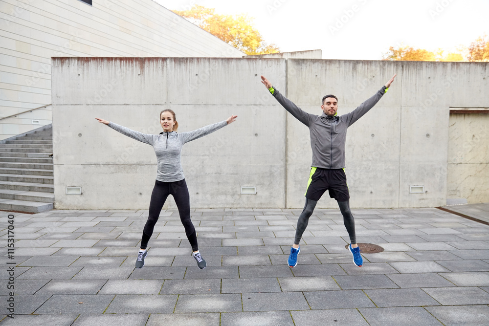 Poster happy man and woman jumping outdoors