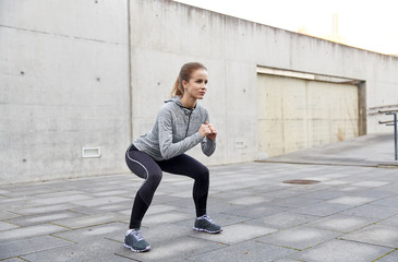 happy woman doing squats and exercising outdoors