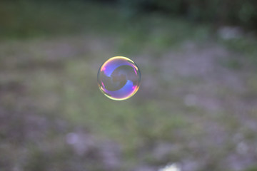 Soap bubble reflecting sunset colors and garden in the background.